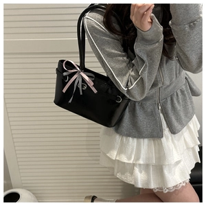 Détail du sac cabas en cuir verni noir avec nœuds en soie rose et motifs à carreaux