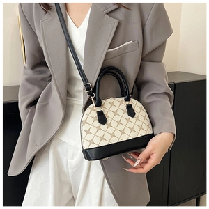 Detail of vintage shell handbag with beige monogram canvas and black leather handles
