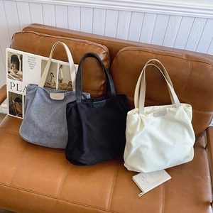 Corduroy tote bags in grey, black, and beige with leather fashion label on sofa