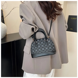 Detail of gray shell bag with diamond texture, gold hardware and adjustable strap