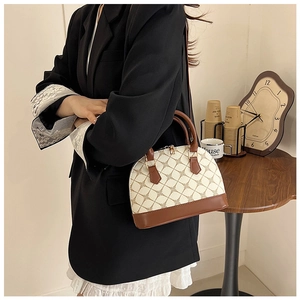 Detail of vintage beige shell bag with geometric patterns and brown leather handles