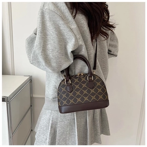 Detail view of a vintage shell handbag with geometric pattern on a model's shoulder