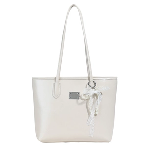 Sac cabas minimaliste crème en simili cuir avec un charm noeud perlé sur fond blanc