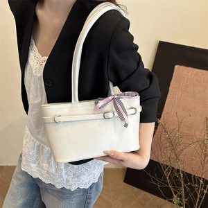 Elegante borsa sottobraccio bianca in vernice con fiocco in nastro su una modella