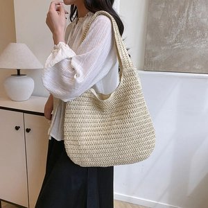 Minimalist beige handmade straw tote bag for beach and daily use shown on shoulder