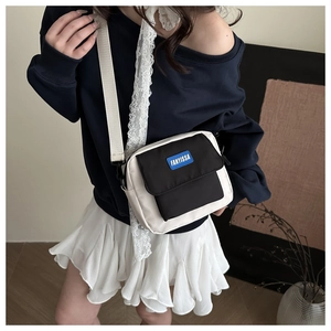 Model wearing a minimalist black and white canvas crossbody bag with adjustable strap