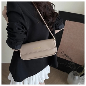 Detail view of a beige baguette bag with gold FASHION & BAGS text and slim shoulder strap