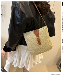 Detail view of woven straw crossbody bag with brown leather strap on model