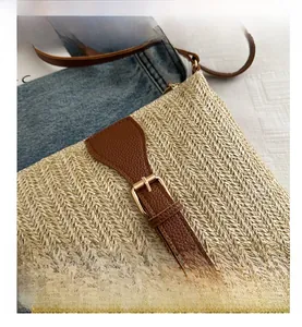 Detail of bohemian woven straw bag with brown lychee leather strap and metal buckle