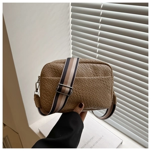 Detail of caramel woven texture small crossbody bag with striped wide fabric strap