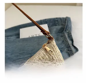 Close-up of woven straw bag showing smooth gold zipper and brown leather details