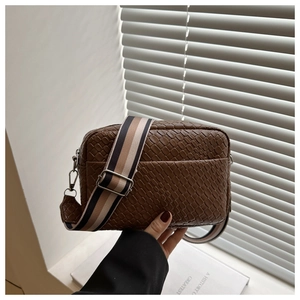 Detail of brown woven texture crossbody bag with adjustable wide fabric shoulder strap