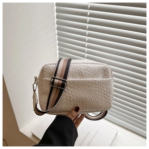 Detail of off-white woven shoulder bag featuring a stylish wide striped fabric strap