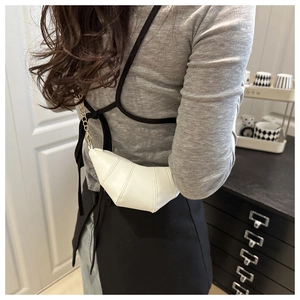 Modèle portant un sac bandoulière croissant en cuir blanc avec détail de chaîne