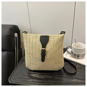 Detail of woven straw tote bag with black leather buckle and adjustable strap