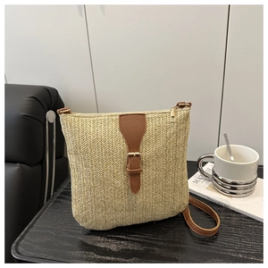 Close-up of woven straw handbag featuring tan leather straps and fine herringbone texture