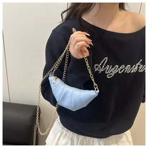 Sac croissant bleu clair à texture matelassée et chaîne dorée porté par un modèle