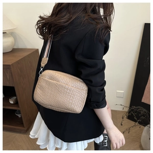 Detail of beige faux crocodile leather texture and striped woven shoulder strap