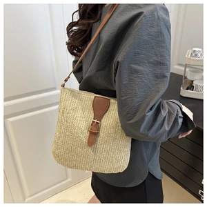 Detail of woven straw crossbody bag with brown faux leather strap and metal buckle