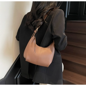 Detail of adjustable metal buckle and soft brown leather texture on a Hobo bag