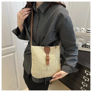 Detail of handwoven straw crossbody bag with brown faux leather strap and buckle