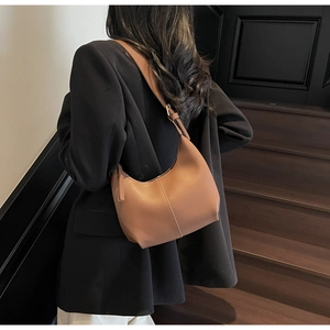Detailed side view of a brown minimalist crescent underarm bag with wide shoulder straps