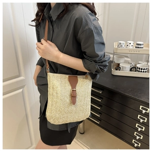 Detail of hand-woven straw crossbody bag with brown leather flap and adjustable strap