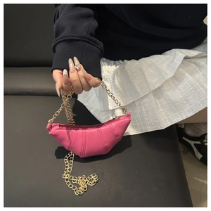 Détail du sac croissant rose avec coutures verticales et bandoulière en chaîne dorée