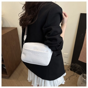 Close-up of a white woven texture bag with wide strap on a model for daily styling