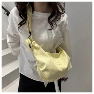Pale yellow crescent crossbody bag made of durable nylon with a round coin purse attached