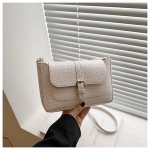 Detail of cream PU crossbody bag featuring woven texture and golden buckle closure