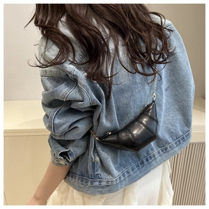 Détail d'un sac croissant noir avec bandoulière chaîne dorée et cuir matelassé