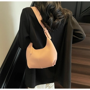 Detail view of pink moon bag on black blazer showing smooth matte leather and minimalist design