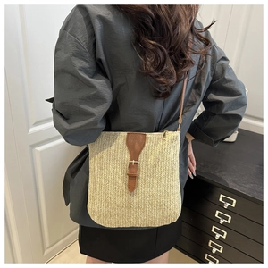 Detalle de bolso bandolera de paja minimalista con correa de cuero llevado por modelo