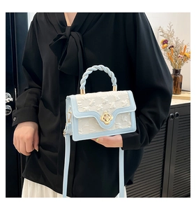 Close-up of vintage blue embossed flower texture and gold clover buckle on the bag