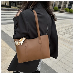 Close-up of vintage brown tote bag featuring a decorative printed silk scarf on the strap