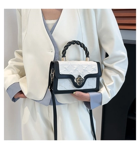 Detail of white embossed crossbody bag with black braided handle and clover metal clasp