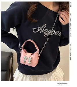Detailed close-up of a mini pink handbag featuring a silver metal bow and chain strap
