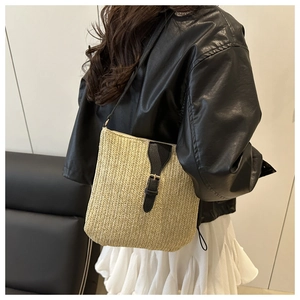 Detail of the beige herringbone straw weave texture with black leather trim and gold buckle