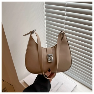 Close-up of minimalist beige crescent bag with silver geometric buckle and smooth leather