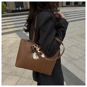Close-up of brown tote bag with decorative patterned scarf and sleek leather texture