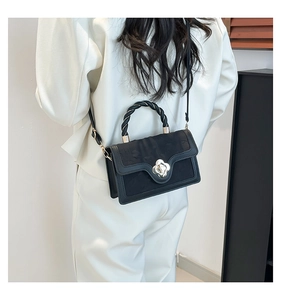Detailed macro view of the black leather textured flap and silver camellia metal buckle