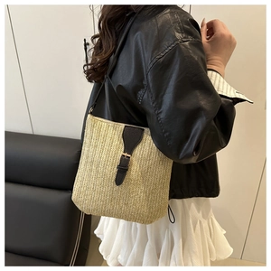 Detalle de bolso bandolera de paja tejida con solapa de cuero negro y hebilla dorada