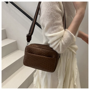 Detail of dark brown woven texture camera bag with adjustable striped wide shoulder strap