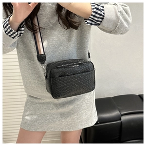 Close-up of black woven leather square bag with a colorful striped wide strap on model