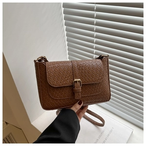 Close-up of dark brown woven leather texture and gold buckle detail on a crossbody bag
