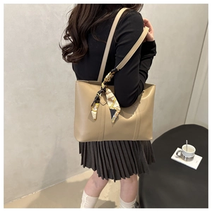 Detail view of large beige tote bag with patterned silk scarf on shoulder strap