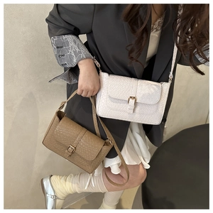 Close-up of animal texture embossed leather shoulder bag with golden metal buckle and flap