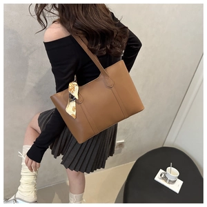 Brown leather tote bag with silk scarf detail shown in a stylish lifestyle setting