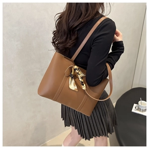 Close-up of brown leather tote bag with decorative patterned scarf on model shoulder